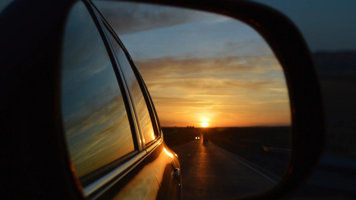 side mirror of a car reflecting a sunset